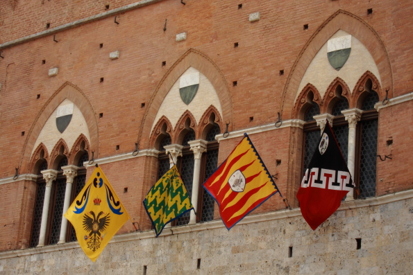 Flagsof the contrade on the front of the Palazzo Publico in Piazza del Campo in Siena, Tuscany in Italy