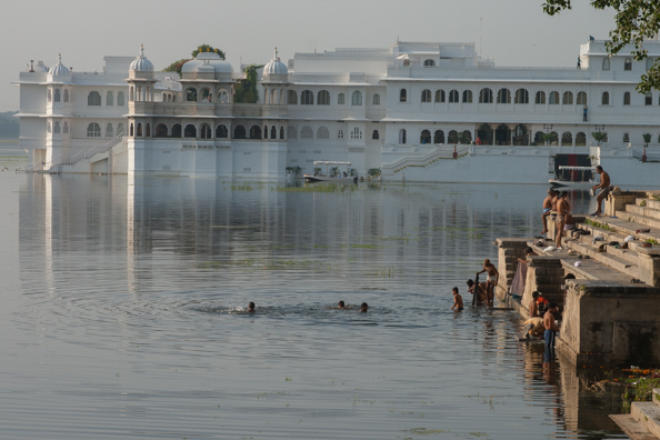 Tow extremes in Udaipur, India - locals washing in the lake and the Lake Palace Hotel
